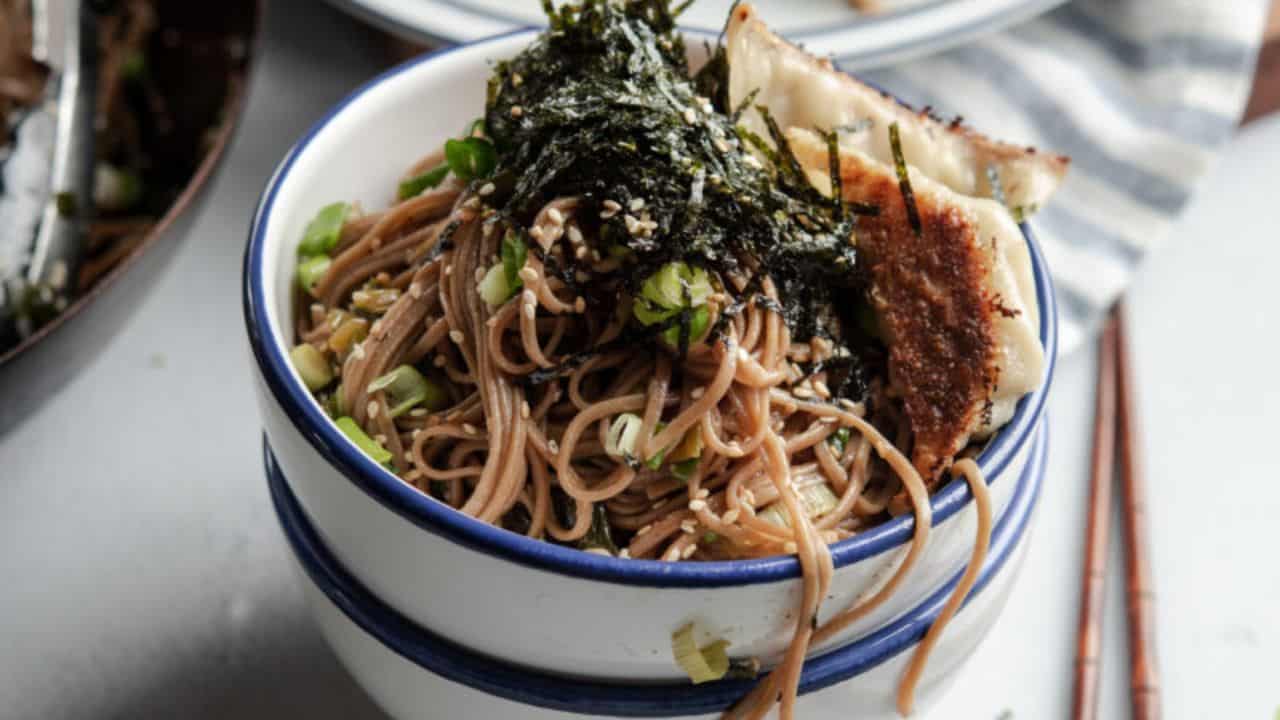 A bowl of sesame soba noodles with dried seaweed.