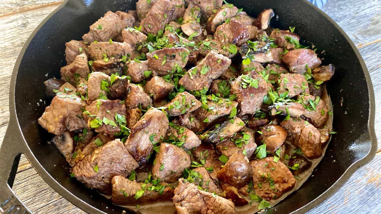 Steak bites on a black skillet.