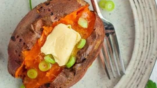 A baked sweet potato topped with butter.