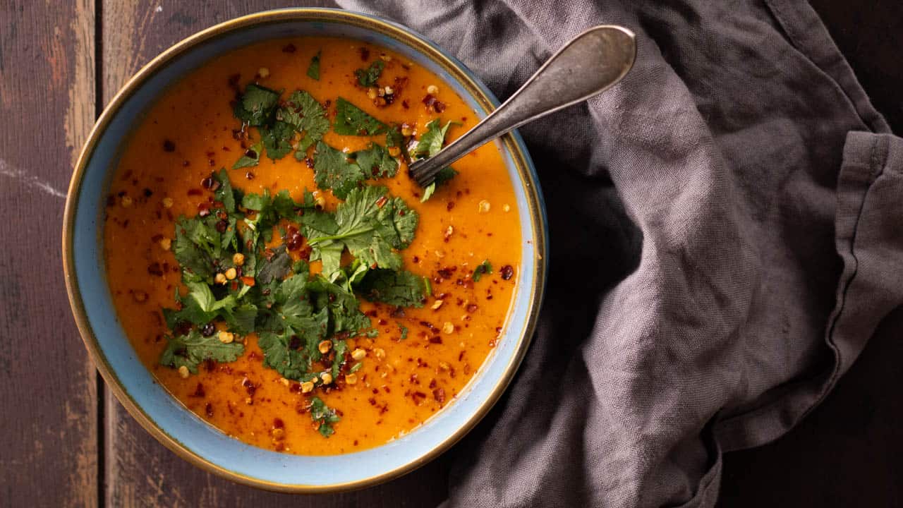 A bowl of lentil soup topped with chili flakes and cilantro.